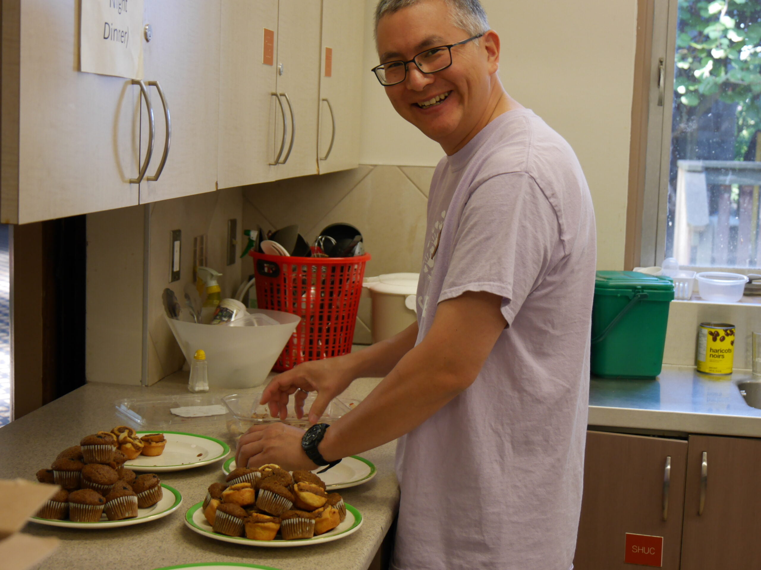 A man prepares a plate of muffins.
