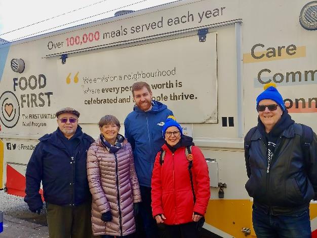 A group of volunteers stands in front of a food truck.